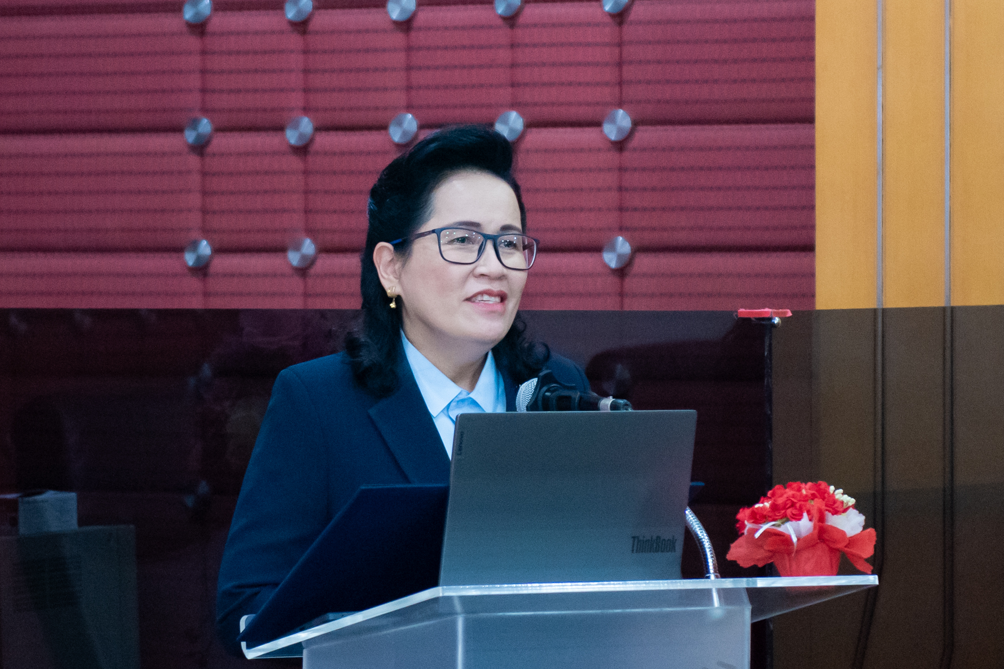 ภาพบรรยากาศ ดร. จุฬารัตน์ ตันประเสริฐ รองผู้อำนวยการ สำนักงานพัฒนาวิทยาศาสตร์และเทคโนโลยีแห่งชาติ ยืนกล่าวคำบรรยายที่โพเดียม
