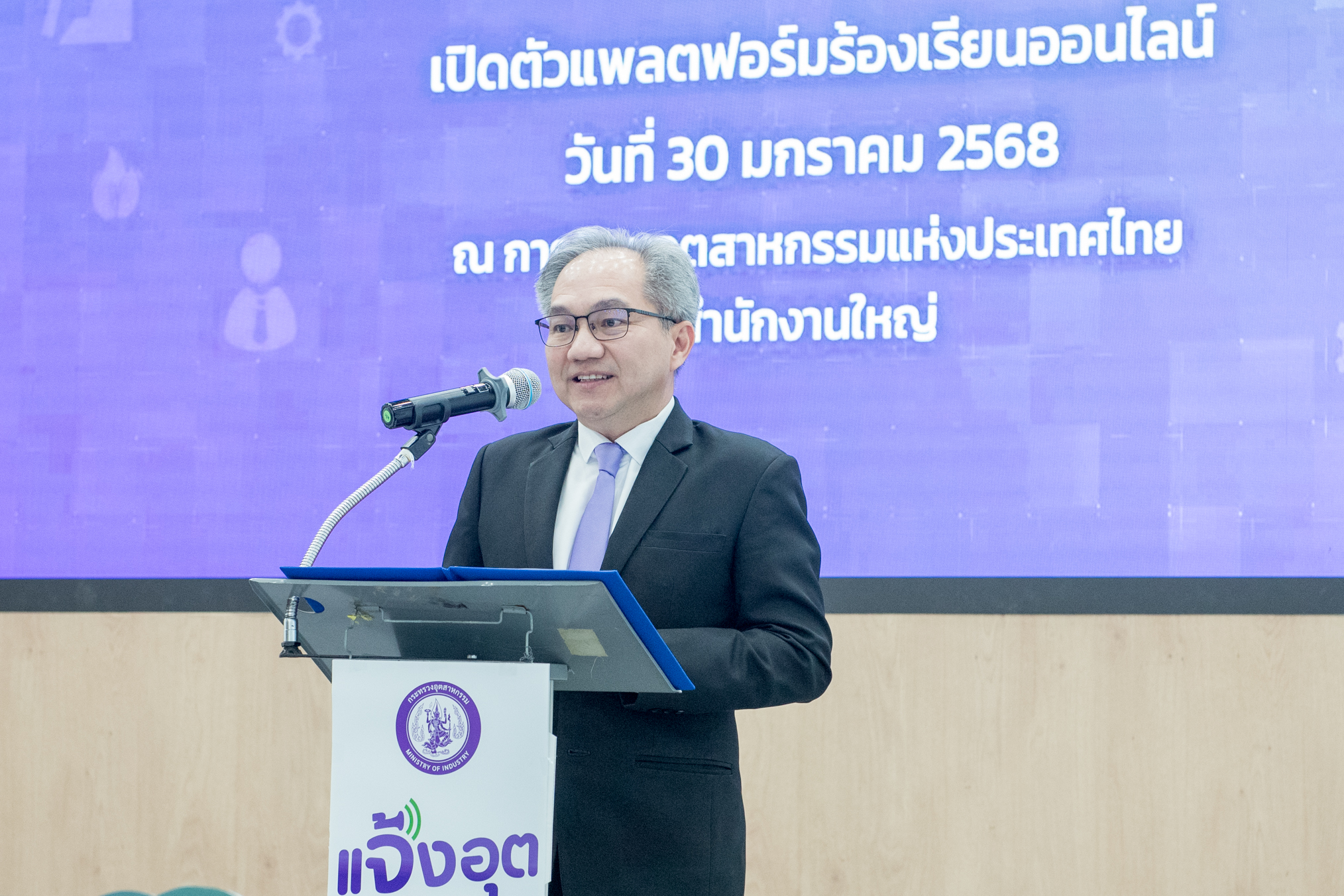 ศาสตราจารย์ ดร.ชูกิจ ลิมปิจำนงค์ ผู้อำนวยการสำนักงานพัฒนาวิทยาศาสตร์และเทคโนโลยีแห่งชาติ ยืนหลังโพเดียม ที่แสดงป้ายแจ้งอุต
