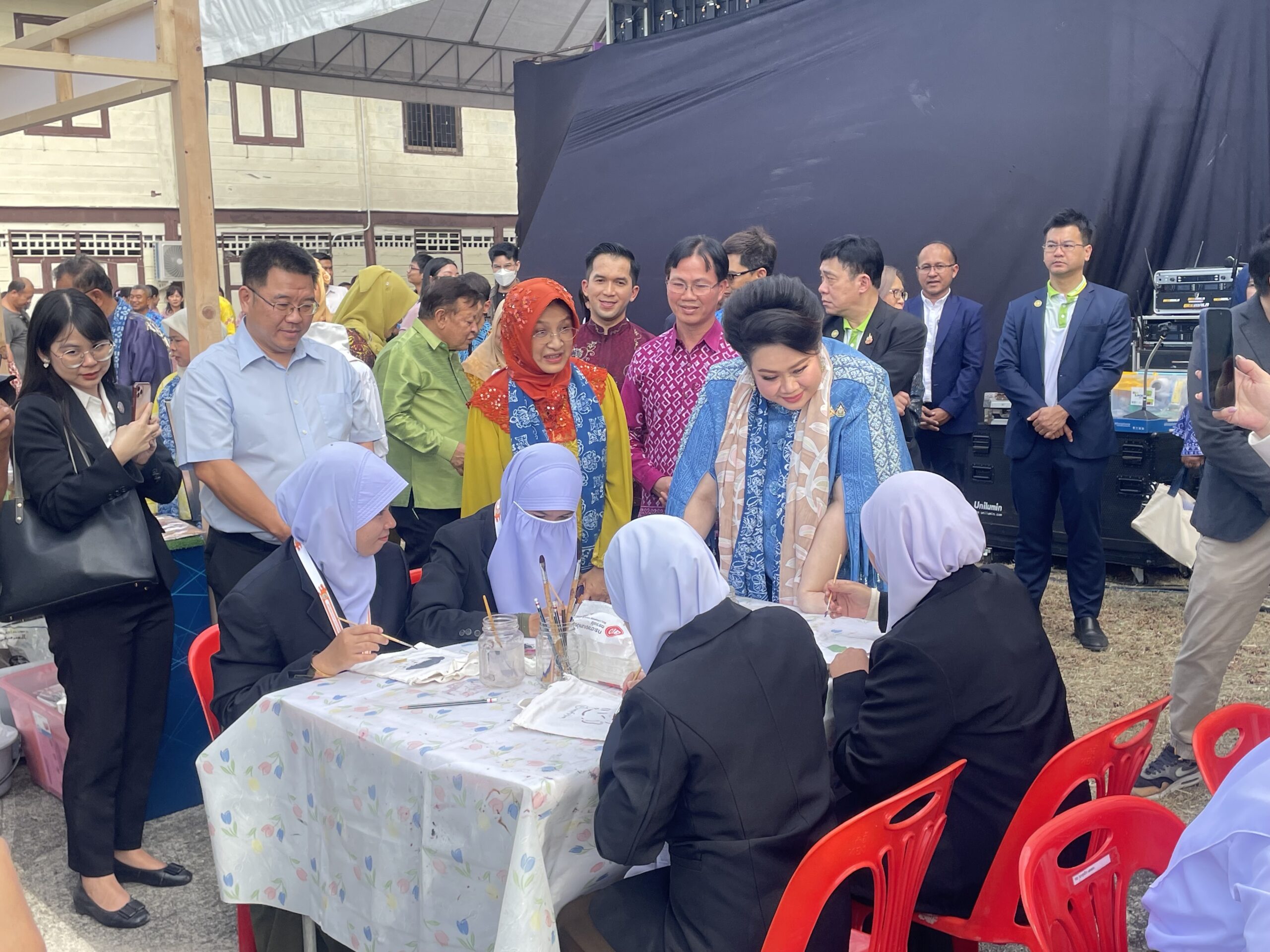 นางสาวศุภมาส อิศรภักดี รัฐมนตรีว่าการกระทรวงการอุดมศึกษา วิทยาศาสตร์ วิจัยและนวัตกรรม (อว.) เดินดูงานการทำนวัตกรรมผ้าบาติก จากการสาธิตวิธีทำจากคนในพื้นที่นวัตกรรมผ้าบาติกล้อมรอบ