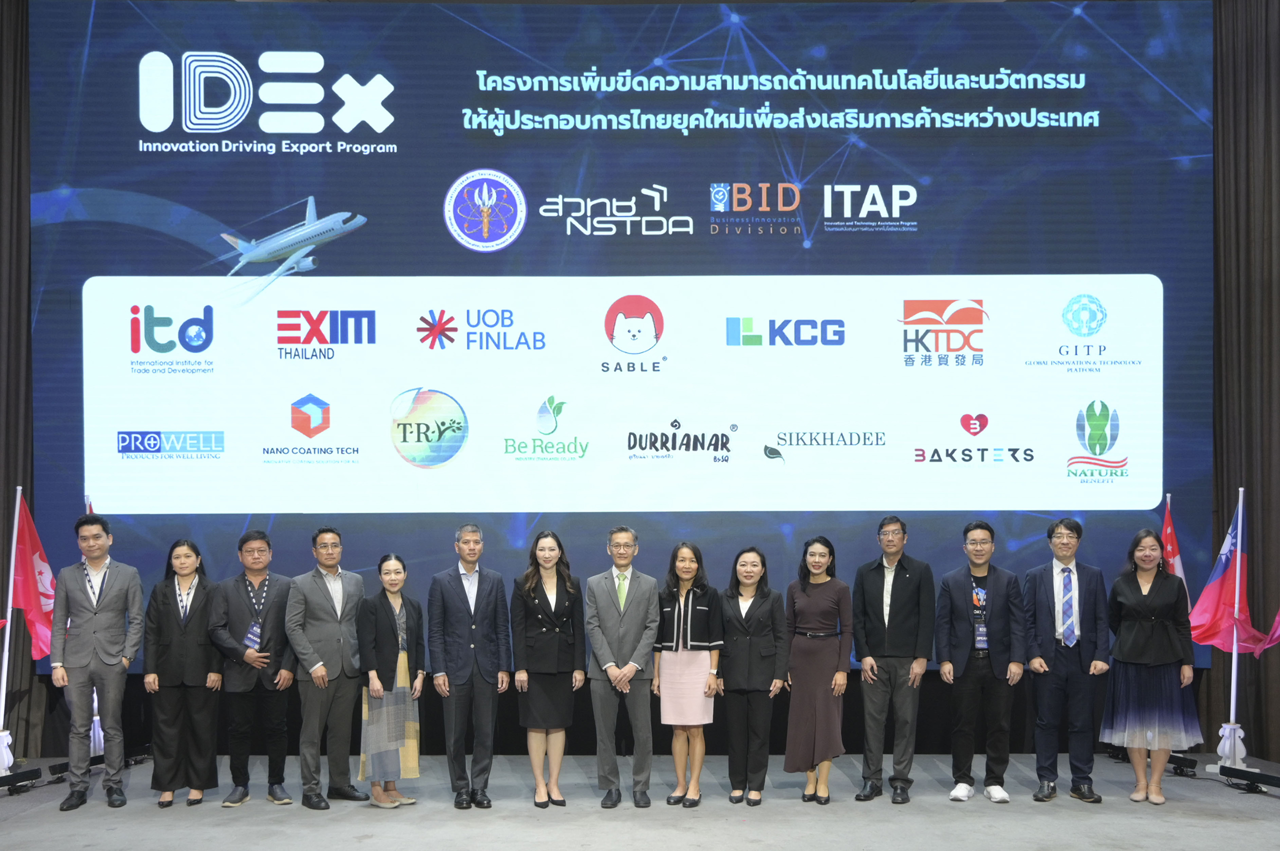 ภาพหมู่ผู้บริหารที่มาร่วมงานทั้งหมด 15 ท่าน บนเวที ฉากหลังมีโลโก้องค์กรที่ร่วมดำเนินการหลายชิ้น