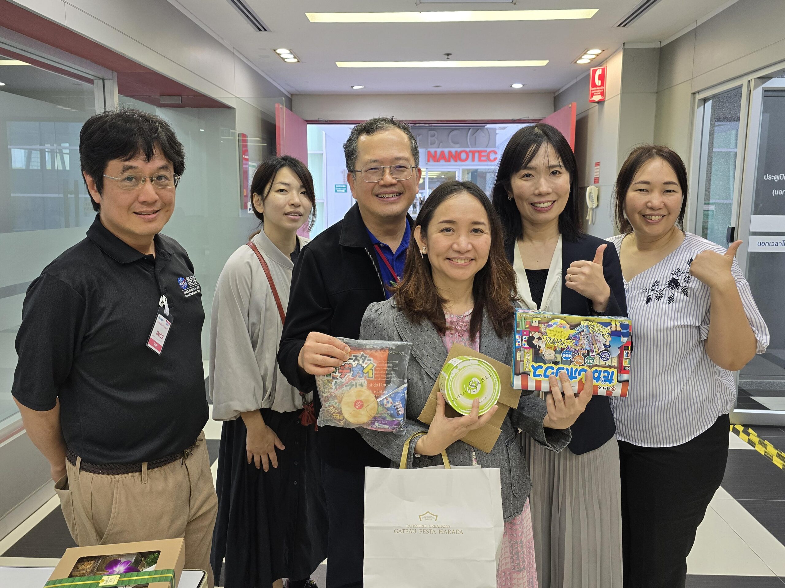 ภาพทีมงาน JAXA และ สวทช. ถ่ายรูปร่วมกัน นำโดย คุณซายากะ อูเมมูระ ผู้จัดการ Space Environment Utilization Center และทีมงาน ร่วมกับ ดร.นำชัย ชีววิวรรธน์ ผู้อำนวยการฝ่ายสร้างสรรค์สื่อและผลิตภัณฑ์ และ คุณฤทัย จงสฤษดิ์ ผู้อำนวยการฝ่ายบริการทางวิชาการและการประเมินหลักสูตรด้านพัฒนากำลังคน โดยโชว์ของฝากจากทาง JAXA