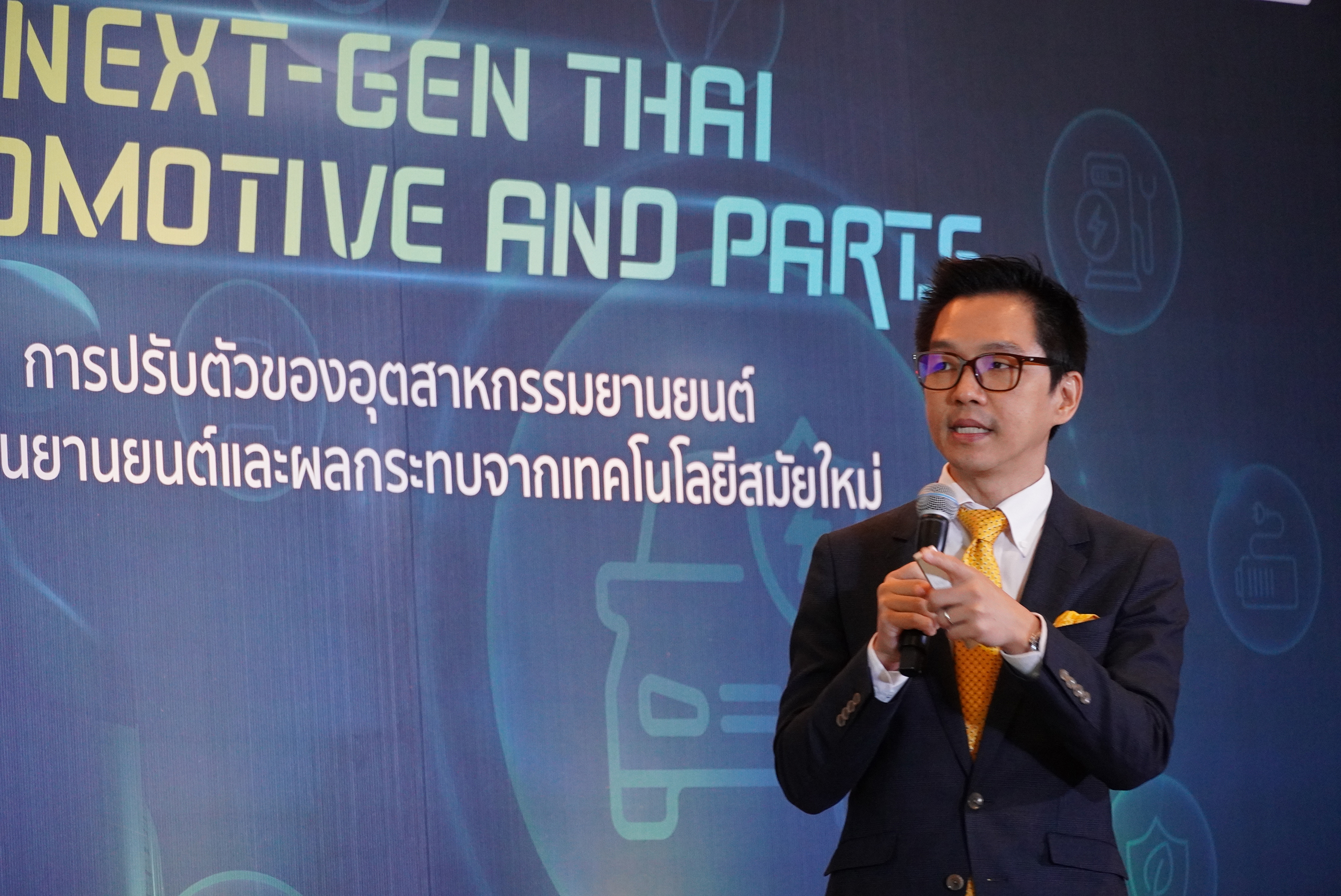 ดร.ศราวุธ เลิศพลังสันติ รอง ผู้อำนวยการ เอ็มเทค ยืนถือไมค์หน้า Backdrop บนเวที กำลังกล่าวถึงแนวโน้มประเทศไทยกับเทคโนโลยียานพาหนะสมัยใหม่