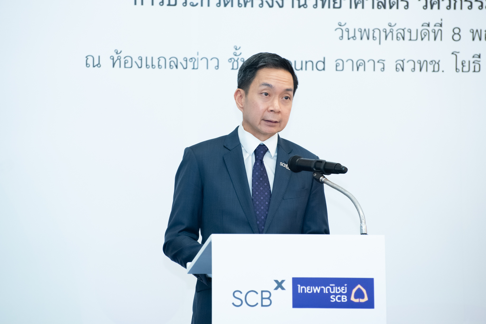ภาพ คุณวรวัจน์ สุวคนธ์ ประธานเจ้าหน้าที่บริหาร สายงานทรัพยากรบุคคล ธนาคารไทยพาณิชย์ จำกัด (มหาชน) กล่าวถึง บทบาทของ SCB ตรงโพเดียมสีขาว บนเวที