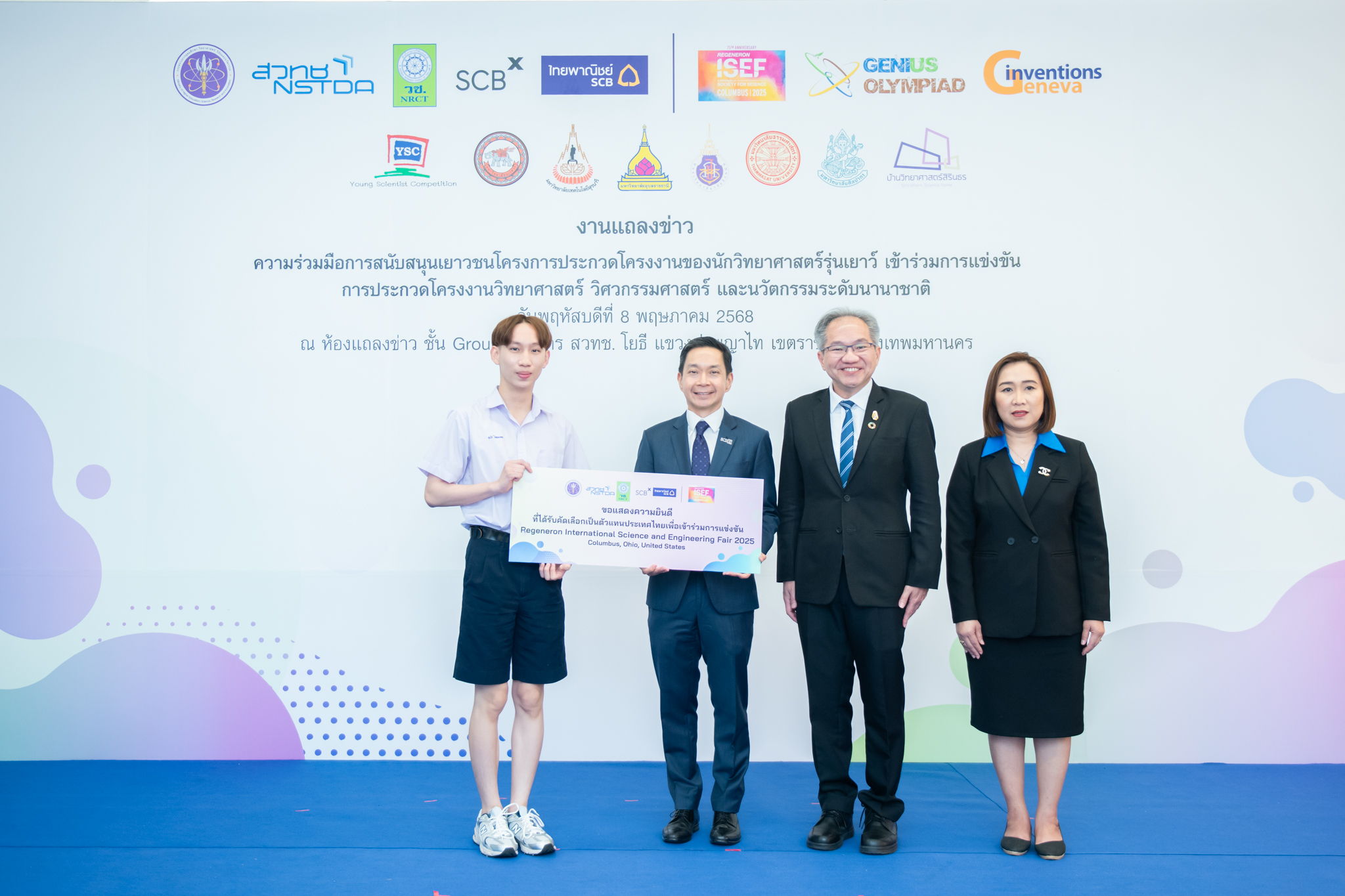 ภาพถ่ายนี้ มีบุคคลทั้งหมด 4 คน ยืนเรียงแถวหน้าฉากหลังที่เป็นแผ่นป้ายงานแถลงข่าว เป็นนักเรียนชาย 1  คน  ในชุดนักเรียนมัธยมปลาย ถือแผ่นป้ายขนาดใหญ่สีขาวเขียนชื่อรางวัล กับผู้บริหาร วช. สวทช  SCB ใส่สูทแบบอย่างการ ทุกคนในภาพยิ้มแย้ม ยืนใกล้กันอย่างเป็นทางการ