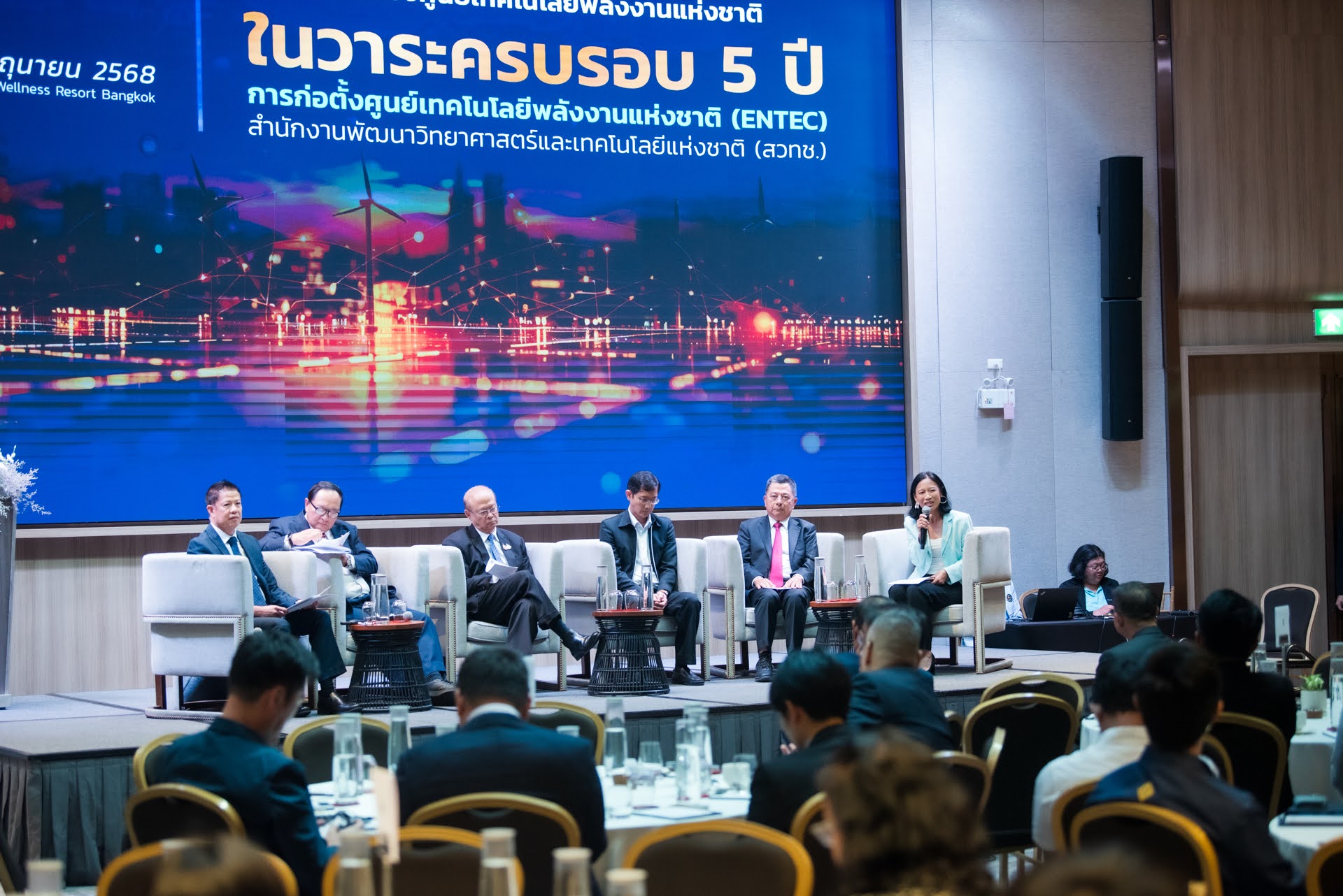 ภาพ บรรยากาศในงานสัมมนา ผู้ร่วมเสวนาทั้ง 5 ท่าน นั่งเก้าอี้โซฟาบนเวที ด้านหลังเป็น Backdrop LED ของงาน ด้านหน้าเป็นผู้เข้าร่วมสัมมนา