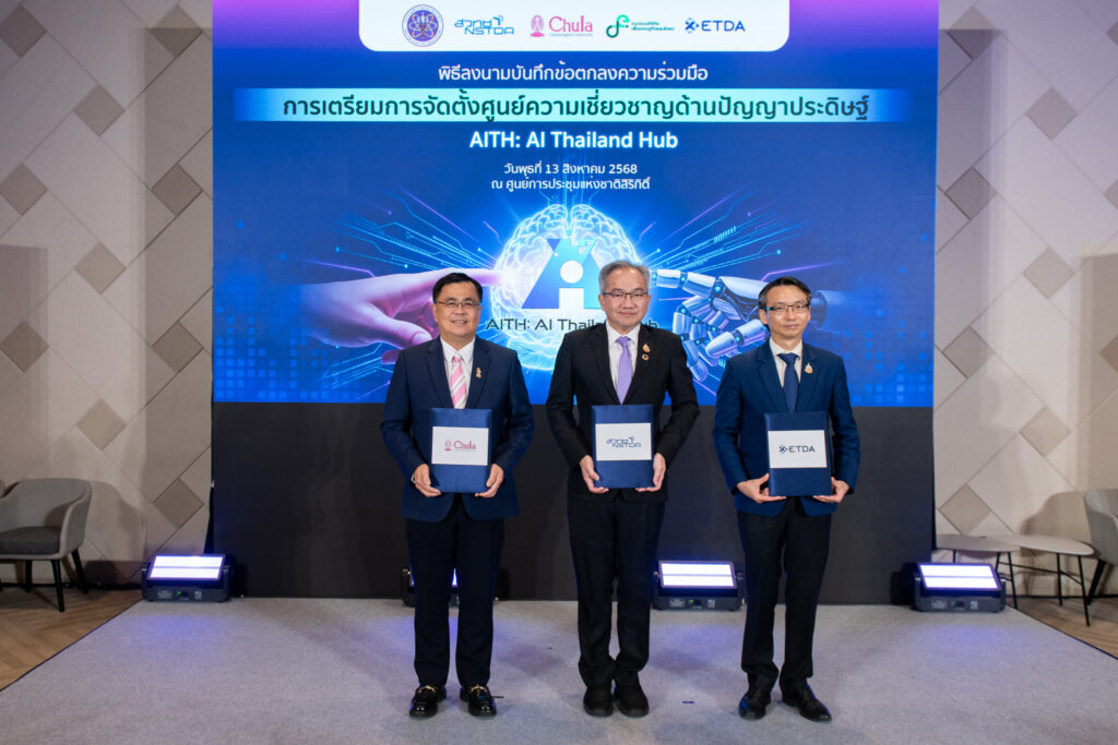 ศาสตราจารย์ ดร.ชูกิจ ลิมปิจำนงค์ ผู้อำนวยการ สวทช. ยืนจับเล่ม สวทช., ศาสตราจารย์ ดร.วิเลิศ ภูริวัชร อธิการบดีจุฬาฯ ยืนจับเล่ม จุฬาฯ, และ ดร.ชัยชนะ มิตรพันธ์ ผู้อำนวยการ สพธอ. ยืนจับเล่ม สพธอ. ด้านหลังเป็น Blackdrop พิธีลงนามความร่วมมือเตรียมการจัดตั้ง AI Thailand Hub 
