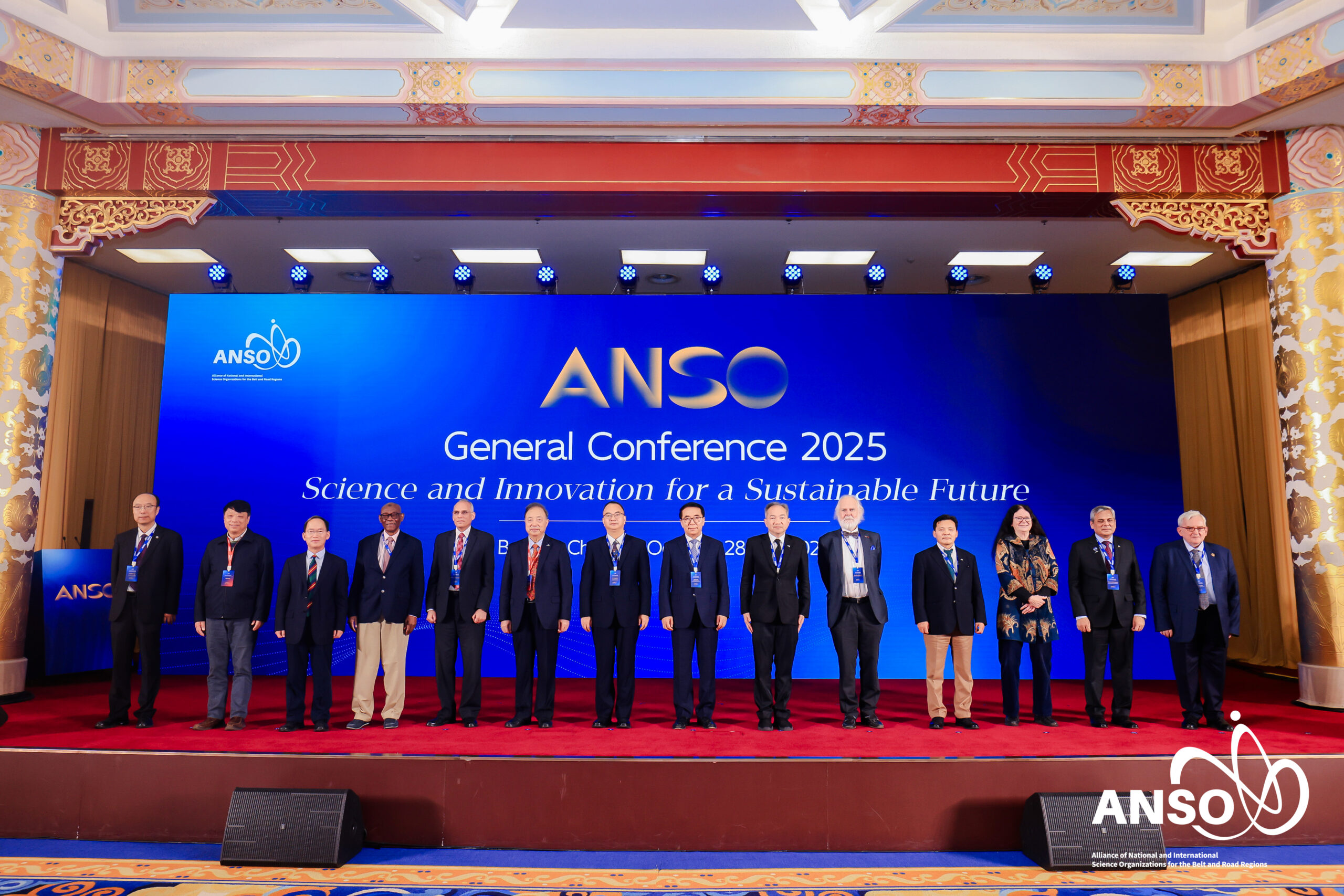 ภาพหมู่ขนาดกว้าง เห็น ผู้บริหารนานาประเทศ ประมาณ 14 คน กำลังยืนบนเวที ที่ปูพรมแดง ด้านหลังเป็น Backdrop มีชื่องาน ANSO ธีมสีน้ำเงิน