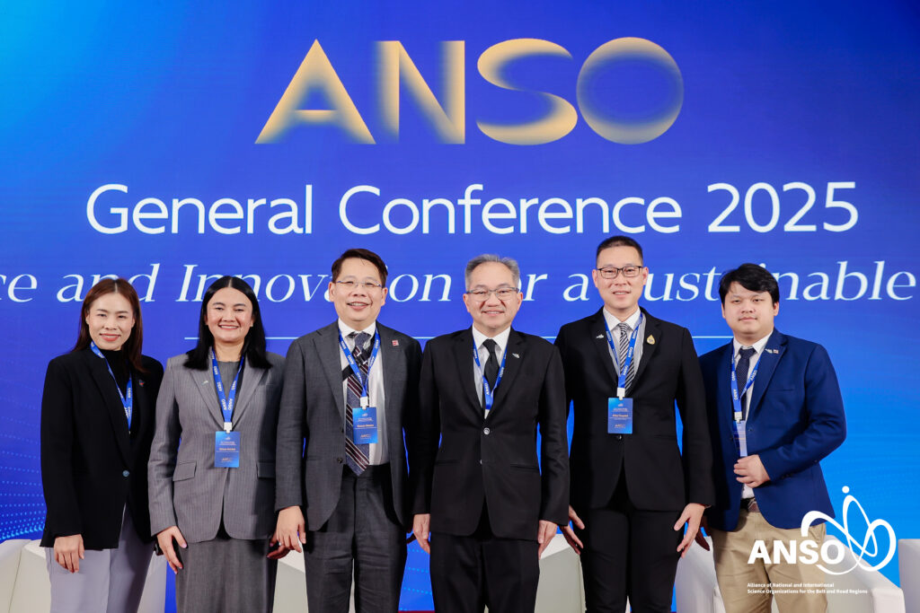 ภาพหมู่ เห็น ผู้บริหาร กำลังยืน ด้านหลังเป็น Backdrop มีชื่องาน ANSO ธีมสีน้ำเงิน