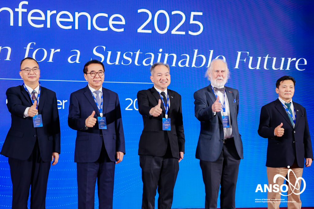 ภาพหมู่ เห็น ผู้บริหารนานาประเทศ  กำลังยืนทำท่ากดไลท์บนเวที ที่ปูพรมแดง ด้านหลังเป็น Backdrop มีชื่องาน ANSO ธีมสีน้ำเงิน