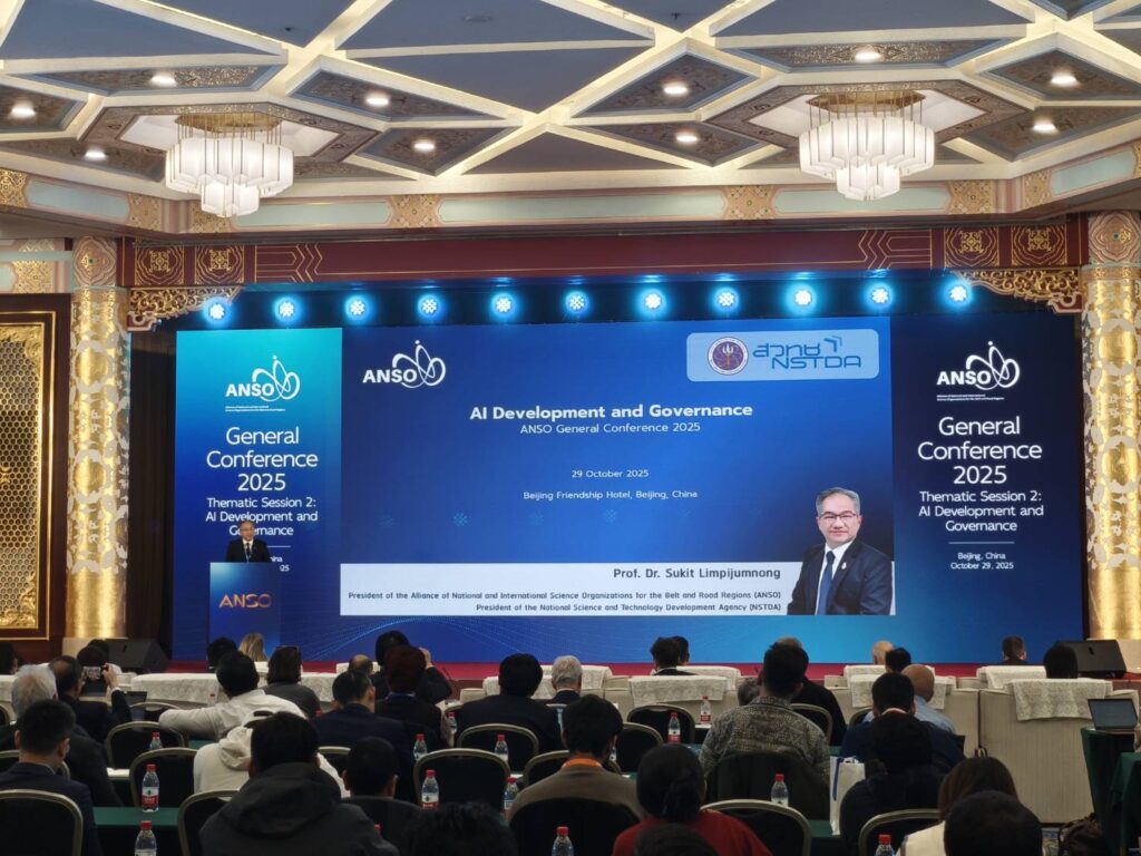 ภาพ ศาสตราจารย์ ดร.ชูกิจ ยืนตรงโพเดี่ยม กำลังพูดด้วยใบหน้ายิ้มแย้ม ด้านหลังเป็นสไลด์นำเสนอ เป็นธีมสีน้ำเงิน