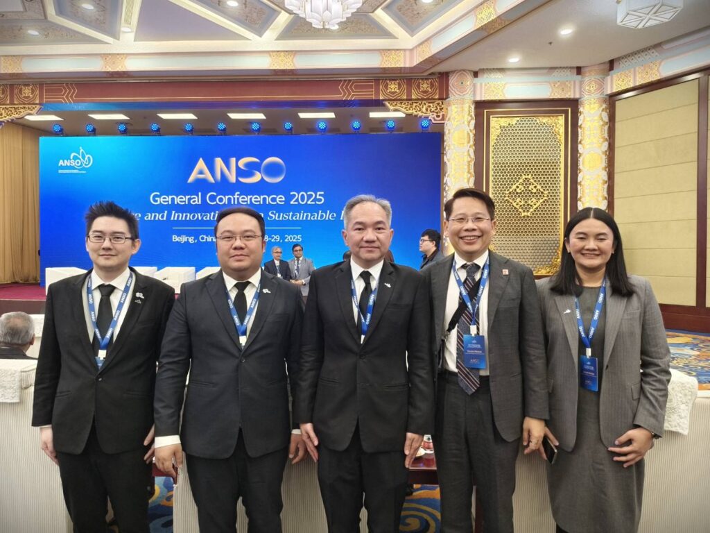 ภาพหมู่ ศาสตราจารย์ ดร.ชูกิจ และท่านอื่นๆ ประมาณ 5 คน ยืนแถวเดียว ด้านหลังเป็น Backdrop มีชื่องาน ANSO ธีมสีน้ำเงิน