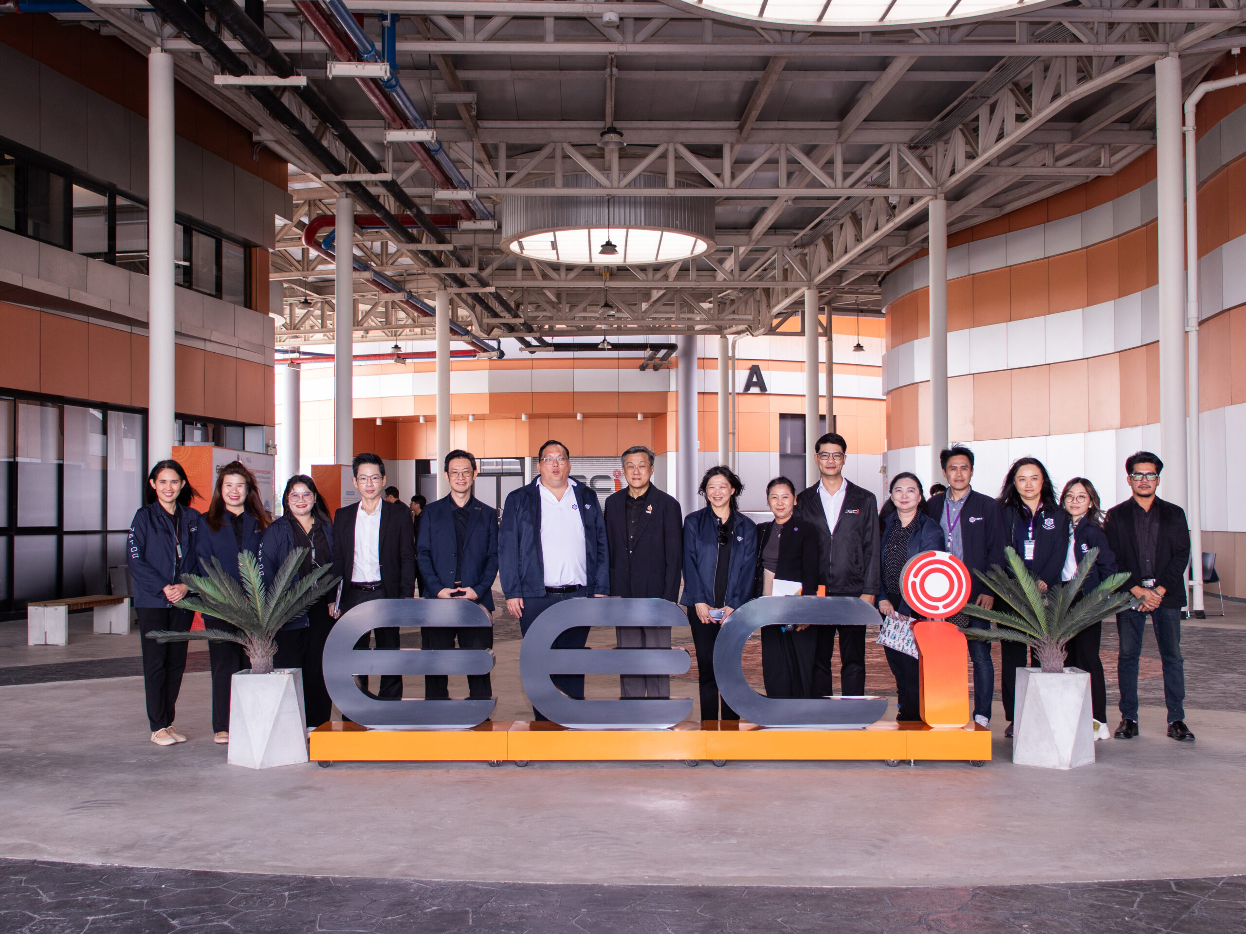 ภาพคณะผู้บริหารและเจ้าหน้าที่จาก สวทช. และ กนอ. ถ่ายร่วมกันหน้าอาคารเขตนวัตกรรม EECi ภายในพื้นที่อาคารลักษณะโมเดิร์น