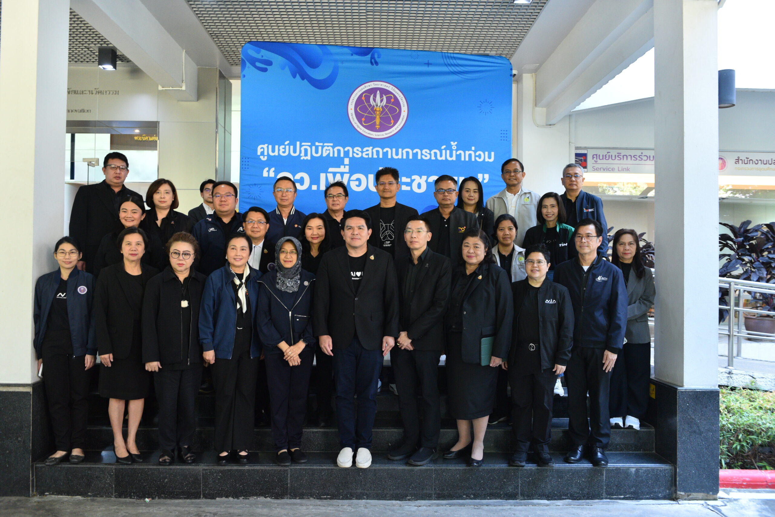 ภาพกลุ่มผู้บริหารและเจ้าหน้าที่กระทรวง อว. ยืนถ่ายภาพร่วมกันหน้าป้ายศูนย์ปฏิบัติการสถานการณ์น้ำท่วม “อว. เพื่อประชาชน”