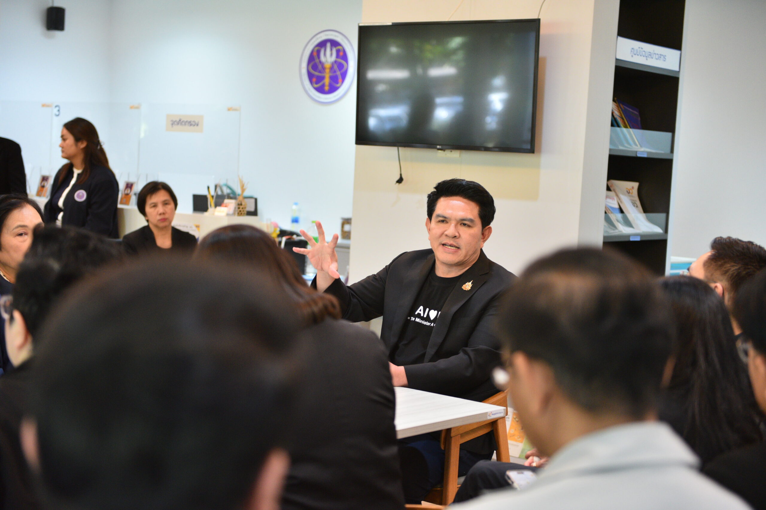 ภาพขบวนรถบรรทุกสิ่งของบริจาคขณะเตรียมออกเดินทาง โดยมีผู้บริหารและเจ้าหน้าที่ อว. ยืนส่งคาราวานช่วยเหลือผู้ประสบภัยน้ำท่วม