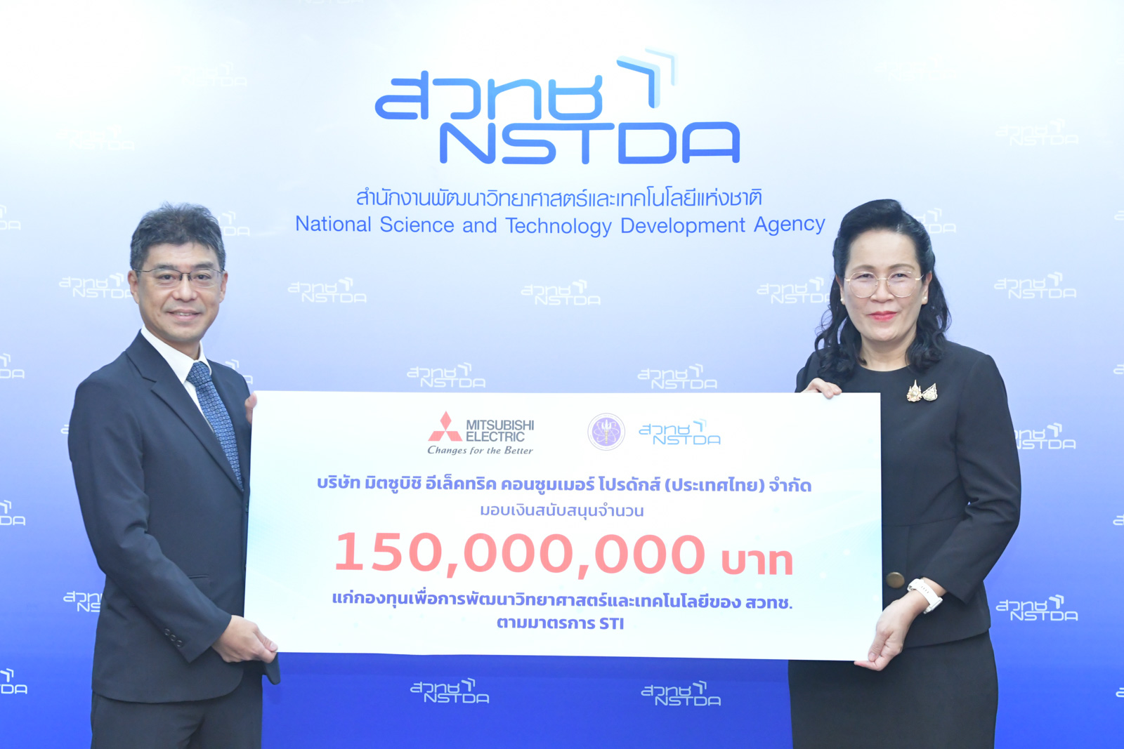 ภาพผู้แทนจากบริษัทเอกชนส่งมอบป้ายเงินสนับสนุนมูลค่า 150 ล้านบาท ให้กับผู้แทน สวทช. ณ ฉากหลังโลโก้ NSTDA