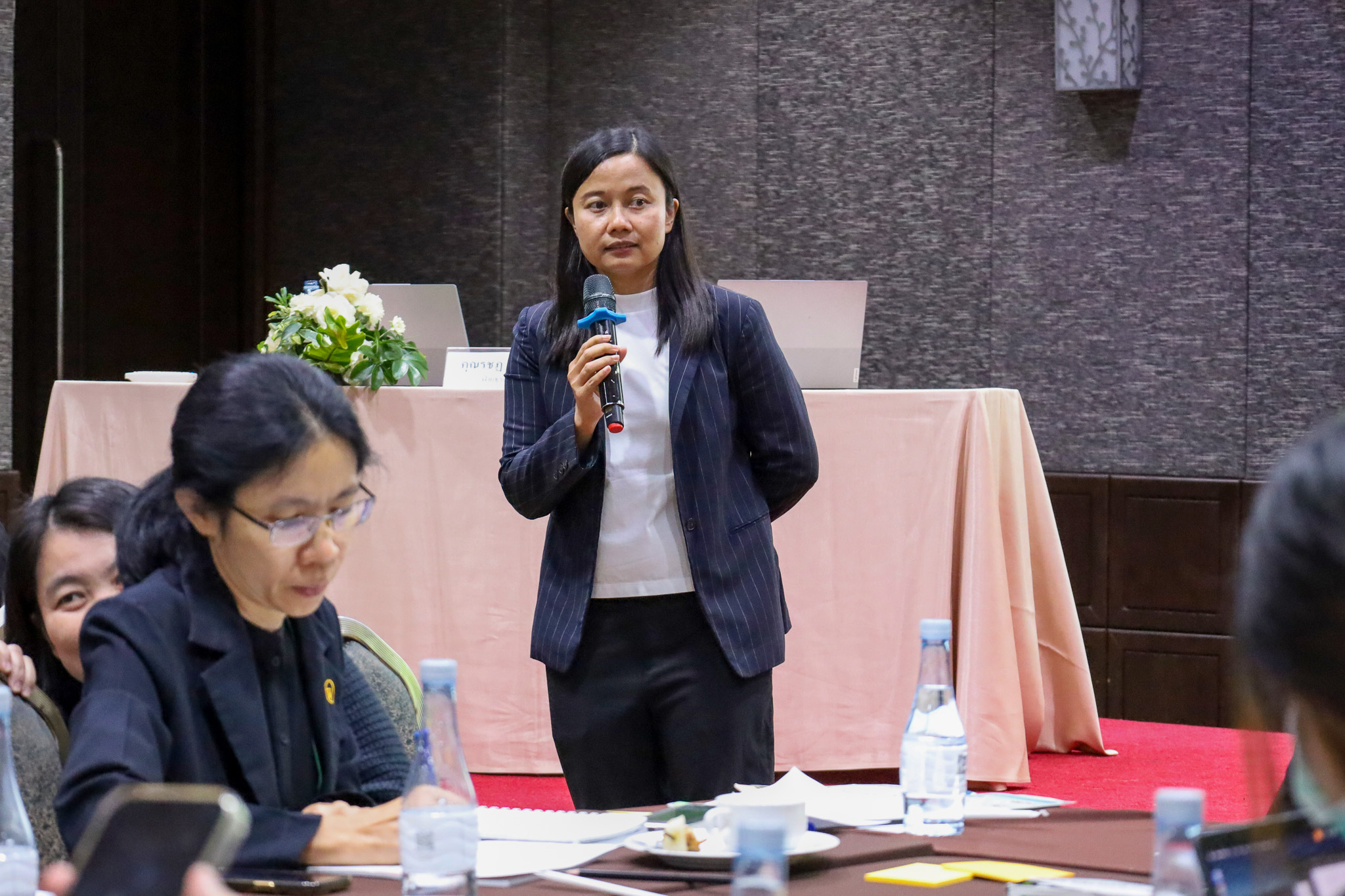 ภาพวิทยากรหญิงลุกขึ้นยืนถือไมโครโฟนกล่าวแสดงความเห็นระหว่างช่วงแลกเปลี่ยนความคิดเห็นในที่ประชุม