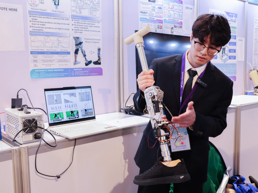 ภาพ นักศึกษากำลังอธิบายผลงานจากการประกวดสิ่งประดิษฐ์สำหรับคนพิการและผู้สูงอายุ ของบูธนิทรรศการ ในงาน