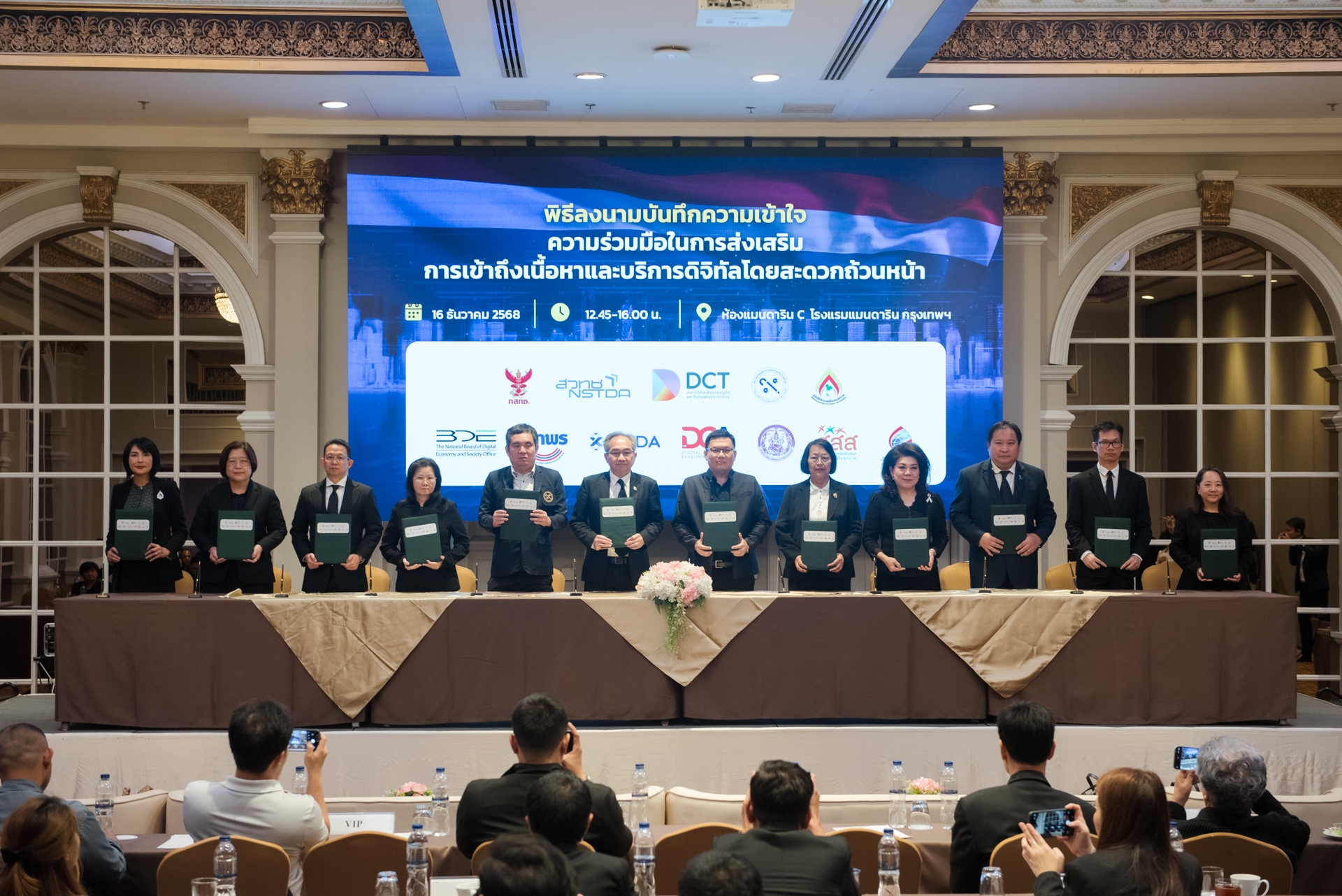 ภาพ: ผู้บริหารจาก 12 องค์กรพันธมิตร ยืนถือแฟ้มบันทึกข้อตกลง (MOU) ร่วมกันบนเวที ภายใต้ความร่วมมือในการส่งเสริมการเข้าถึงเนื้อหาและบริการดิจิทัลโดยสะดวกถ้วนหน้า