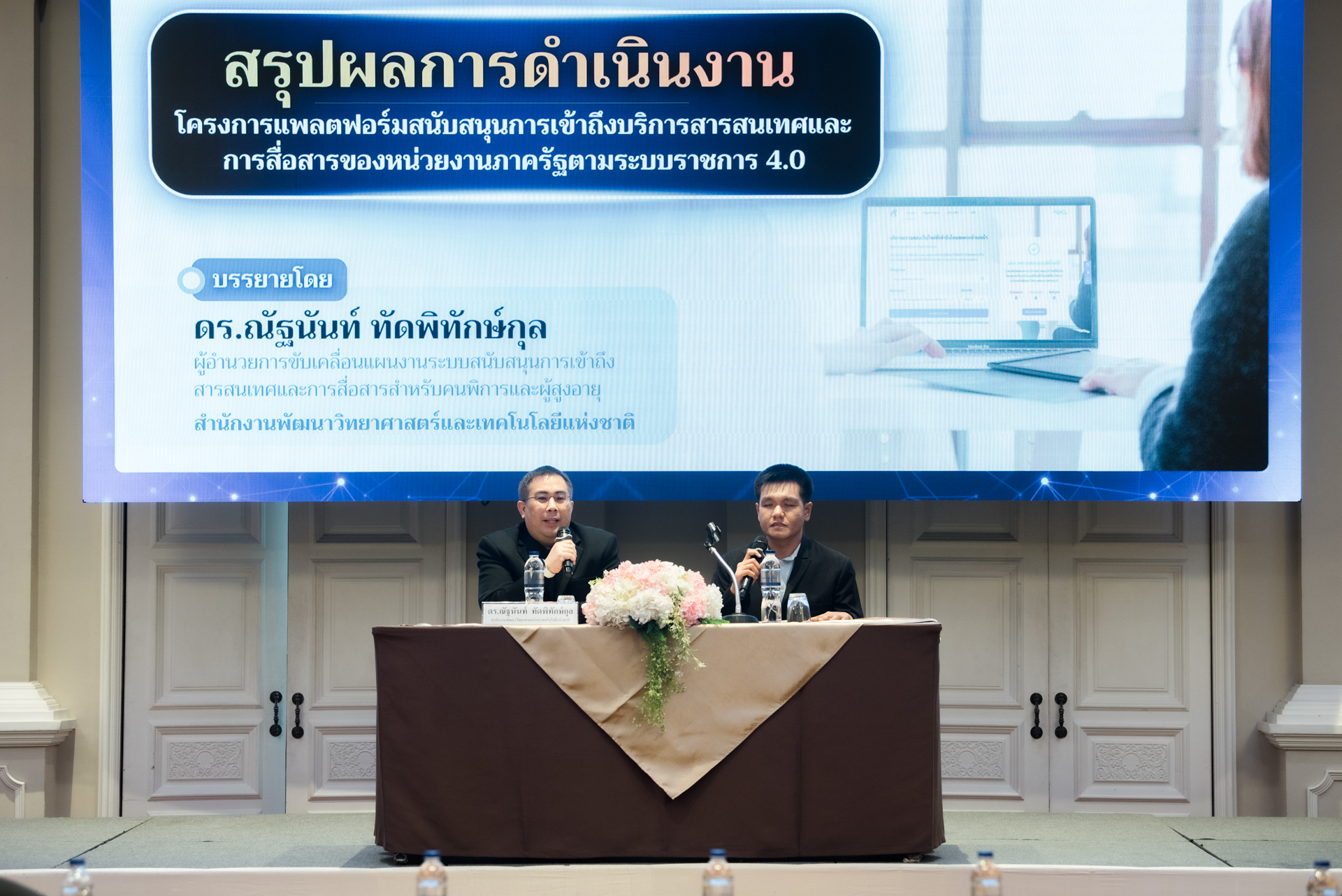 ภาพ: ดร.ณัฐนันท์ ทัดพิทักษ์กุล ผู้อำนวยการฝ่าย สวทช. บรรยายสรุปผลการดำเนินงานโครงการแพลตฟอร์มสนับสนุนการเข้าถึงบริการสารสนเทศฯ บนเวทีคู่กับผู้ดำเนินรายการ