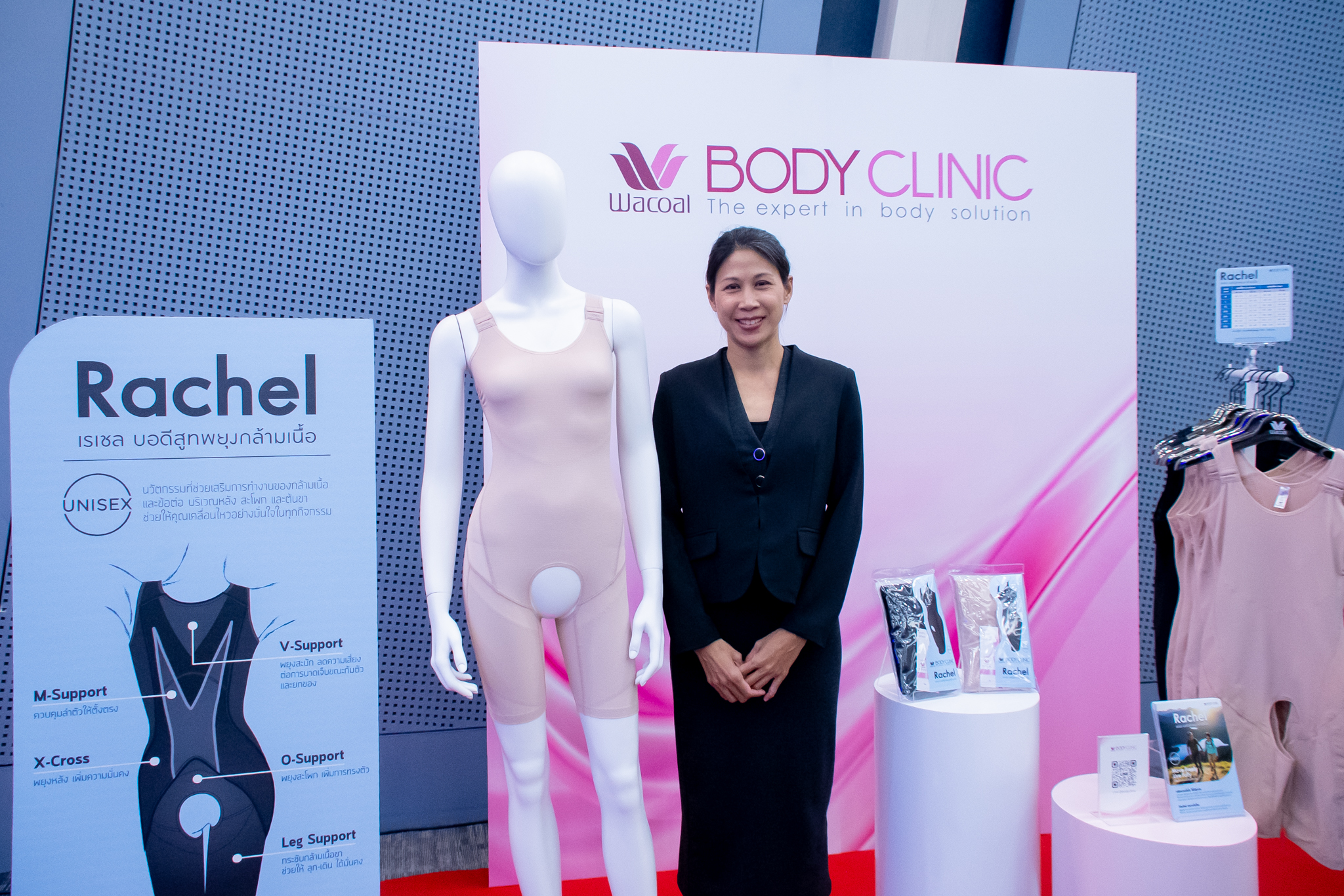 ภาพ นางอินทิรา ยืนท่ามือจับกัน หน้า Backdrop Wacoal ธีมขาวชมพู