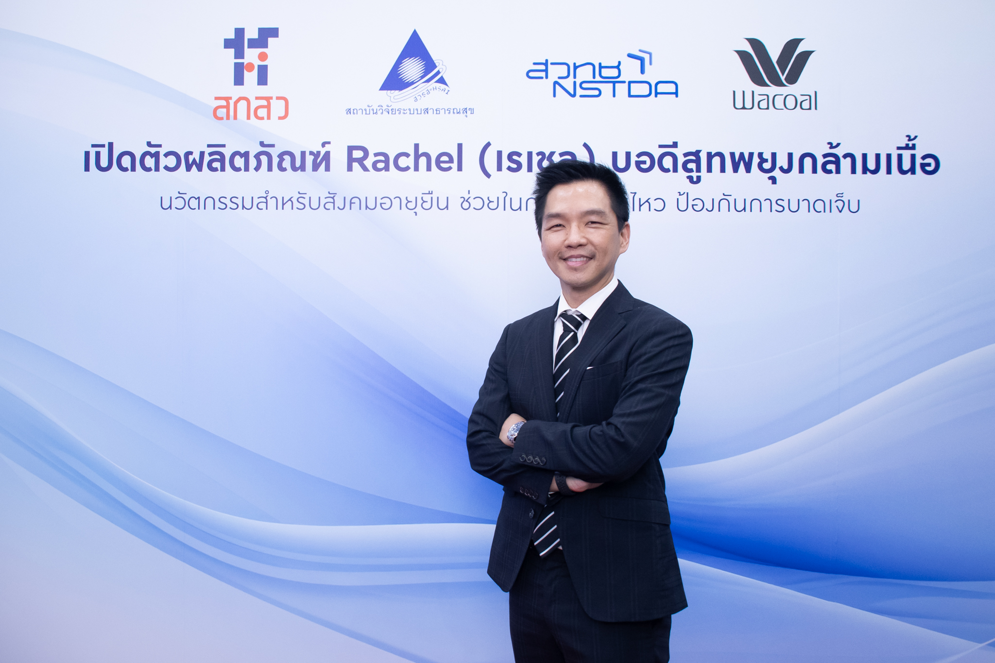 ภาพ ดร.ศราวุธ ยืนท่ากอด หน้า Backdrop งาน ธีมขาวฟ้า