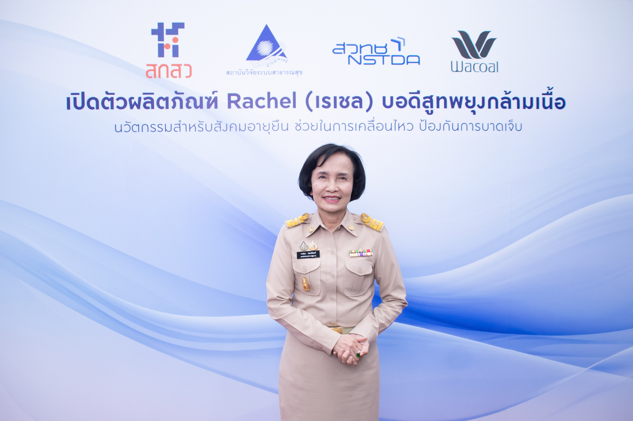 ภาพ นางวาสนา ยืนท่ากอด หน้า Backdrop งาน ธีมขาวฟ้า