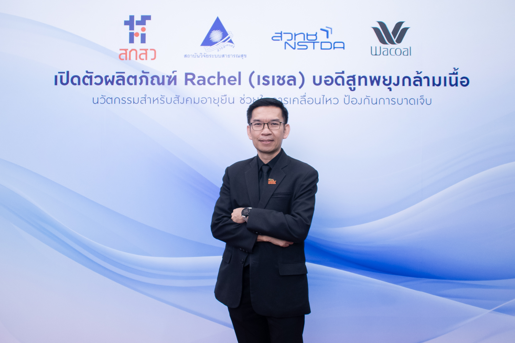 ภาพ นพ.เฉวตสรร ยืนท่ากอด หน้า Backdrop งาน ธีมขาวฟ้า