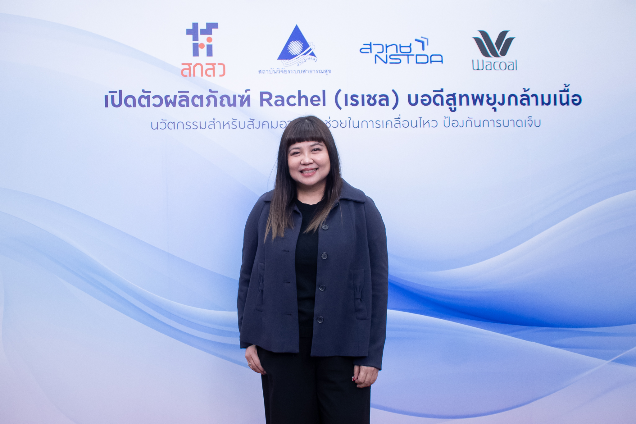 ภาพ นางอินทิรา ยืนท่าตรง หน้า Backdrop งาน ธีมขาวฟ้า