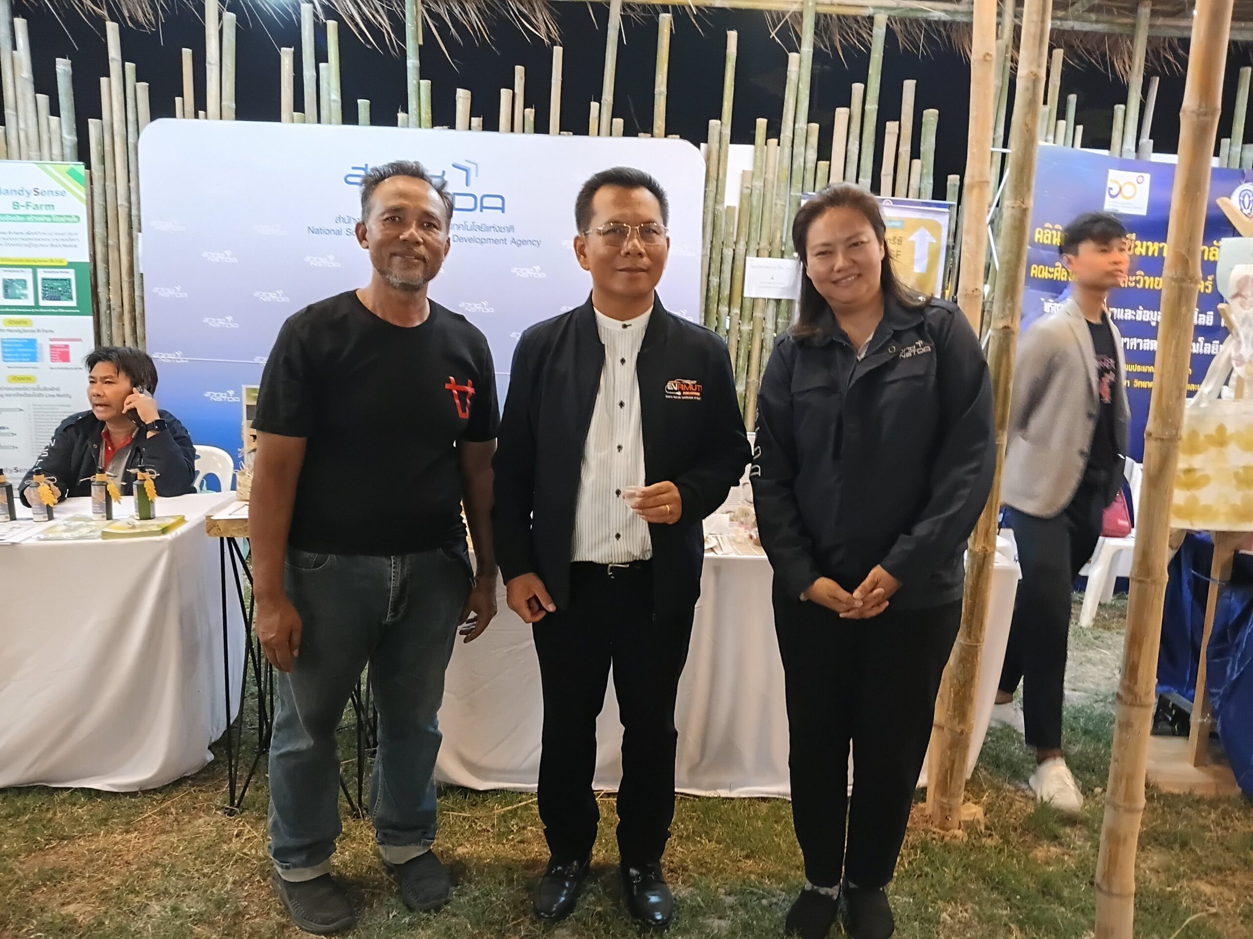 ภาพผู้ร่วมงานถ่ายภาพร่วมกันหน้าบูธแสดงนวัตกรรมของ สวทช. ภายในงานเทศกาลข้าวหอมมะลิโลก ครั้งที่ 25 โดยมีฉากหลังเป็นโปสเตอร์ HandySense และผลิตภัณฑ์นวัตกรรมอาหาร