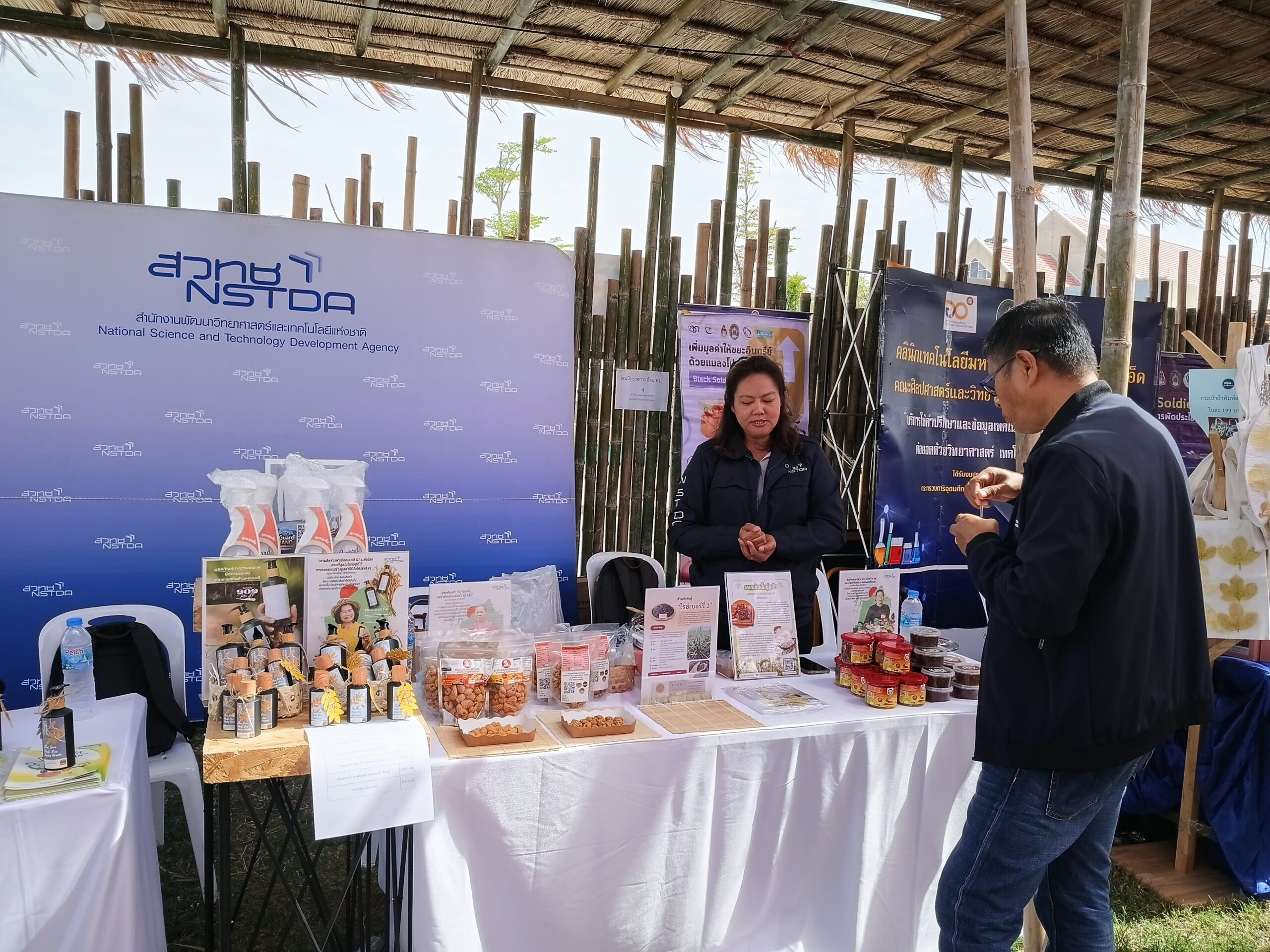 ภาพเจ้าหน้าที่หญิงจาก สวทช. แนะนำผลิตภัณฑ์นวัตกรรมอาหารและสินค้าแปรรูปที่บูธนิทรรศการ ภายในงานเทศกาลข้าวหอมมะลิโลก
