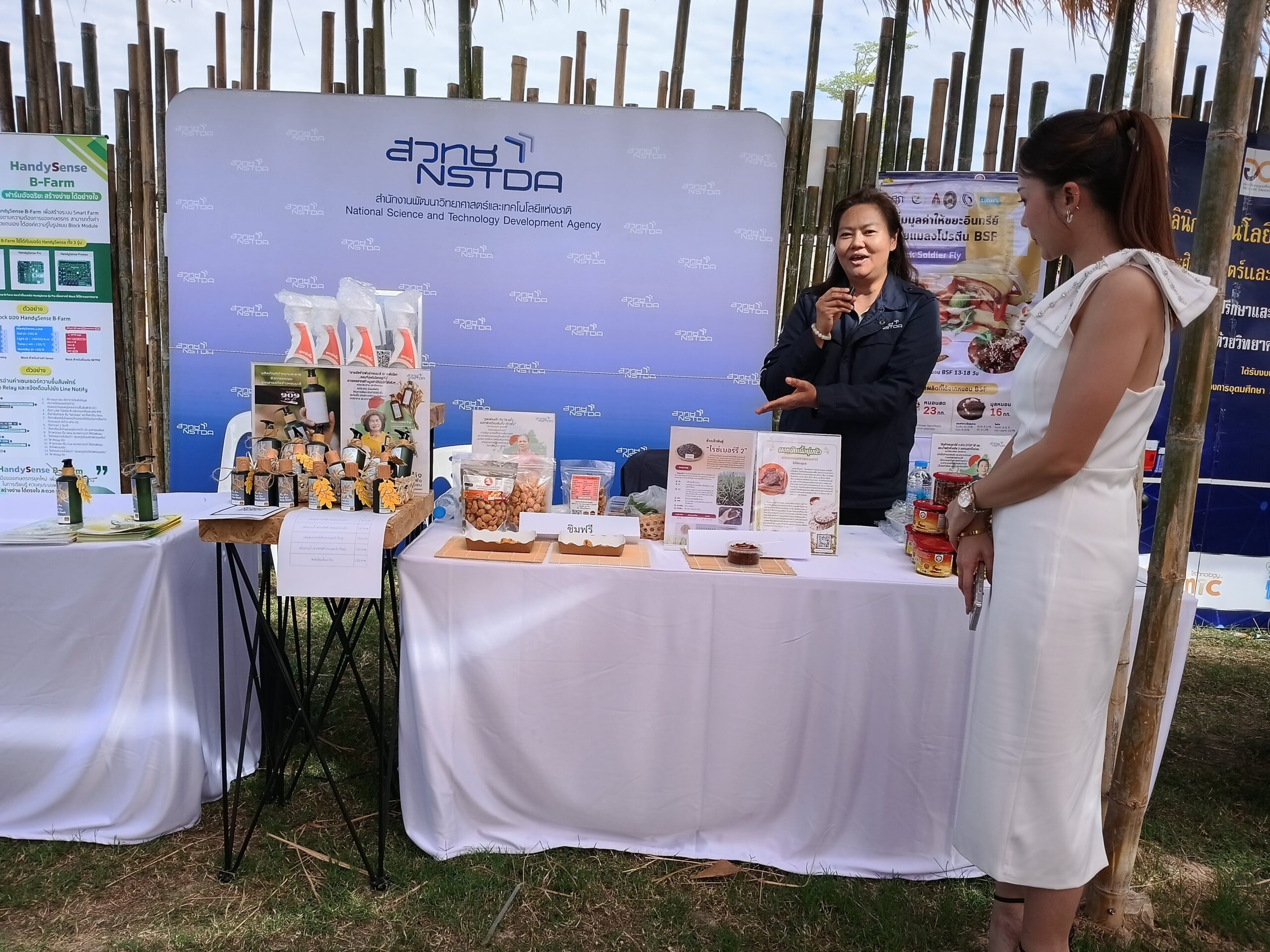 ภาพเจ้าหน้าที่หญิงจาก สวทช. แนะนำผลิตภัณฑ์นวัตกรรมอาหารและสินค้าแปรรูปที่บูธนิทรรศการ ภายในงานเทศกาลข้าวหอมมะลิโลก