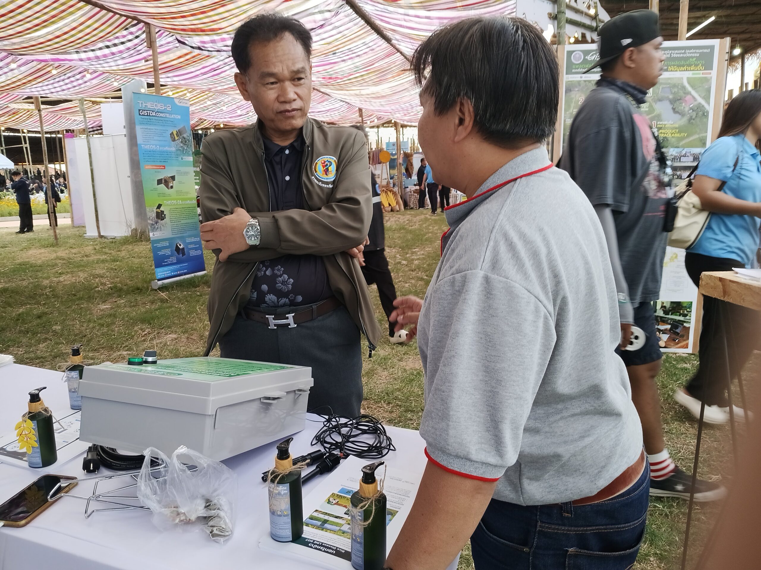 ภาพเจ้าหน้าที่สาธิตการทำงานของระบบ HandySense แก่ผู้สนใจ พร้อมอุปกรณ์วัดสภาพแวดล้อมที่ใช้ในแปลงเกษตรอัจฉริยะ