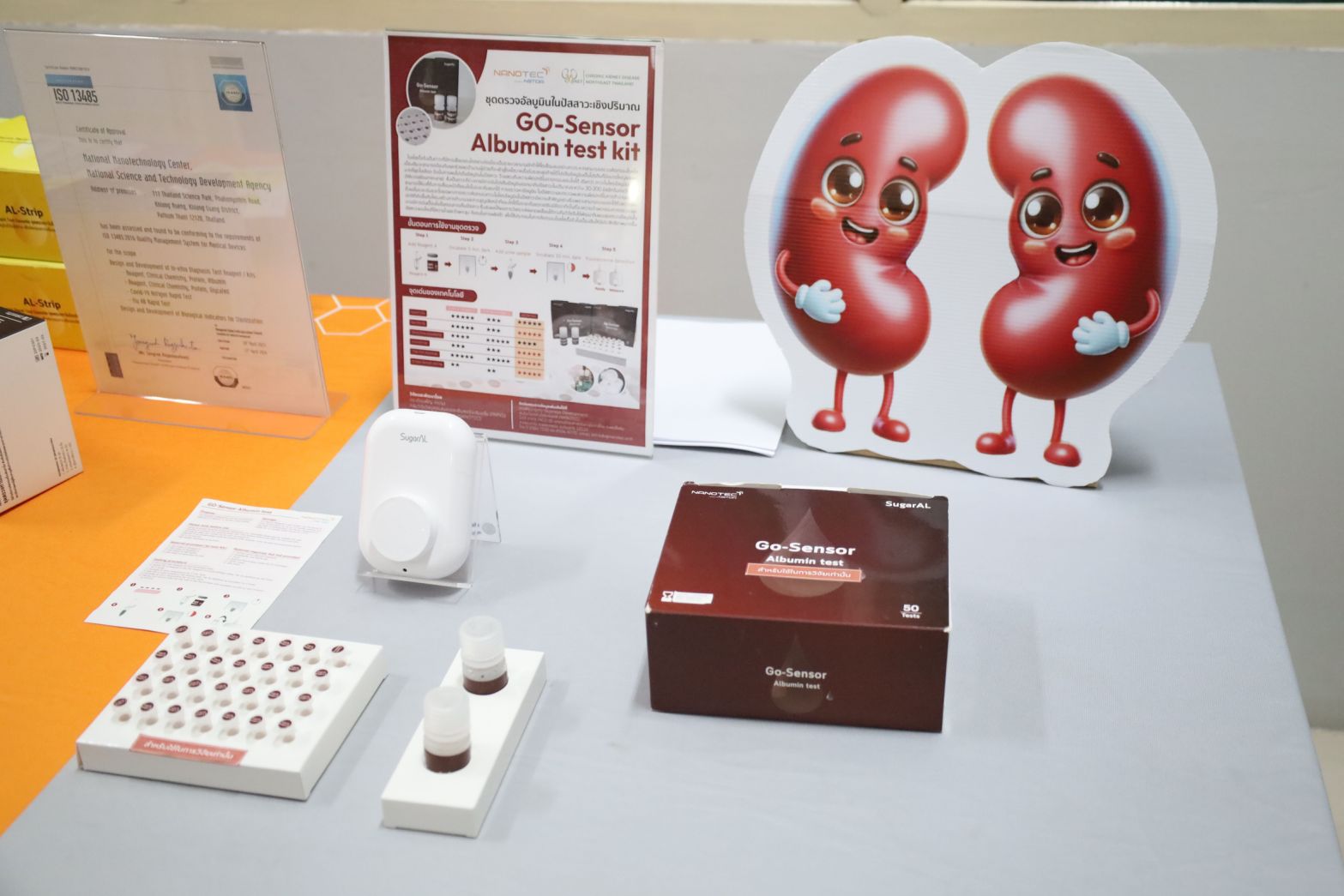 ภาพ: บูธแสดงนวัตกรรมชุดตรวจคัดกรองโรคไต ประกอบด้วยชุดตรวจ GO-Sensor Albumin test kit, เครื่องอ่านค่าแบบพกพา, ตัวอย่างสารทดสอบ