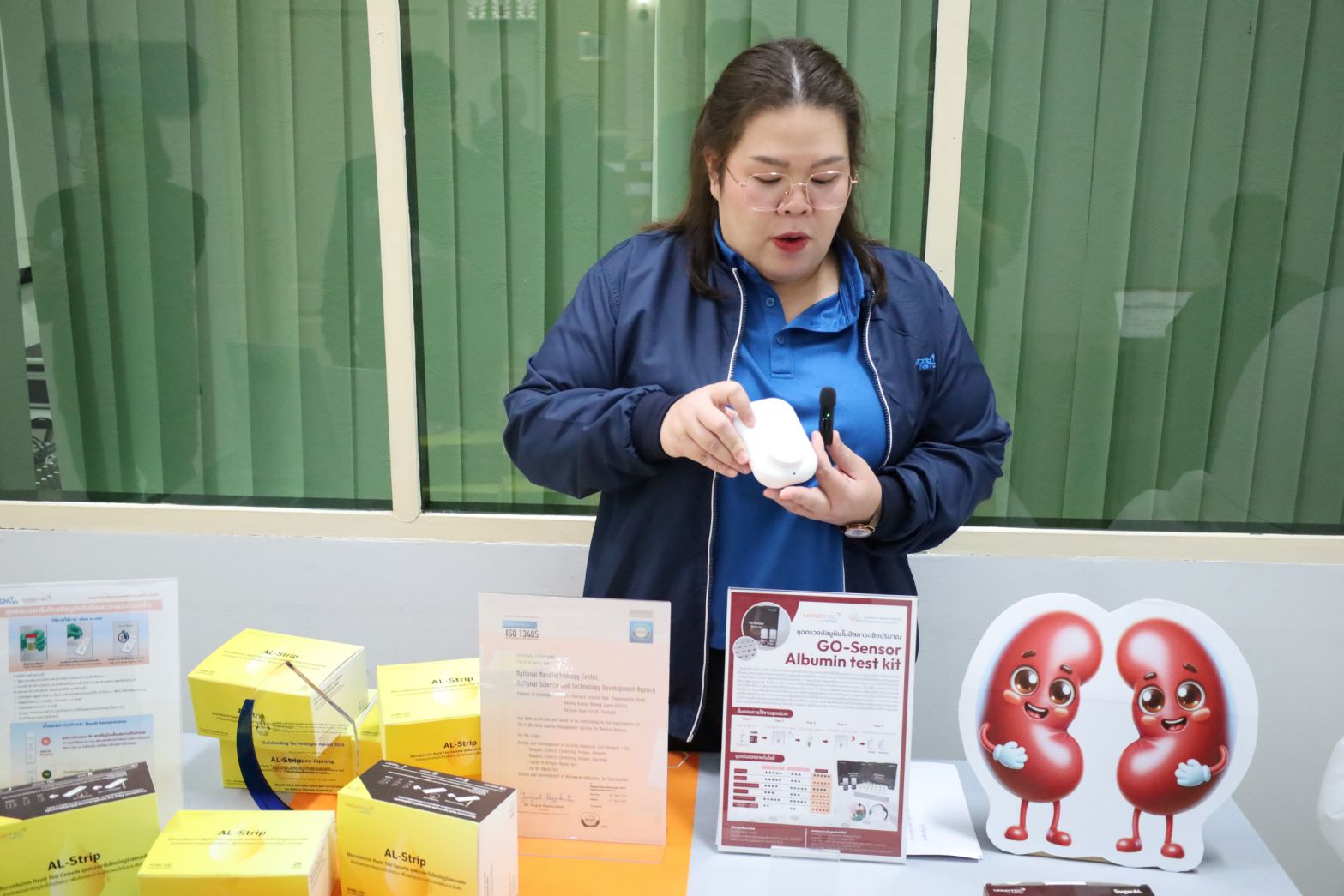 ภาพ: เจ้าหน้าที่จากนาโนเทค สวทช. กำลังสาธิตวิธีการใช้งานเครื่องอ่านค่าผลตรวจจากชุดตรวจคัดกรองโรคไต GO-Sensor ซึ่งมีขนาดกะทัดรัดและพกพาสะดวก