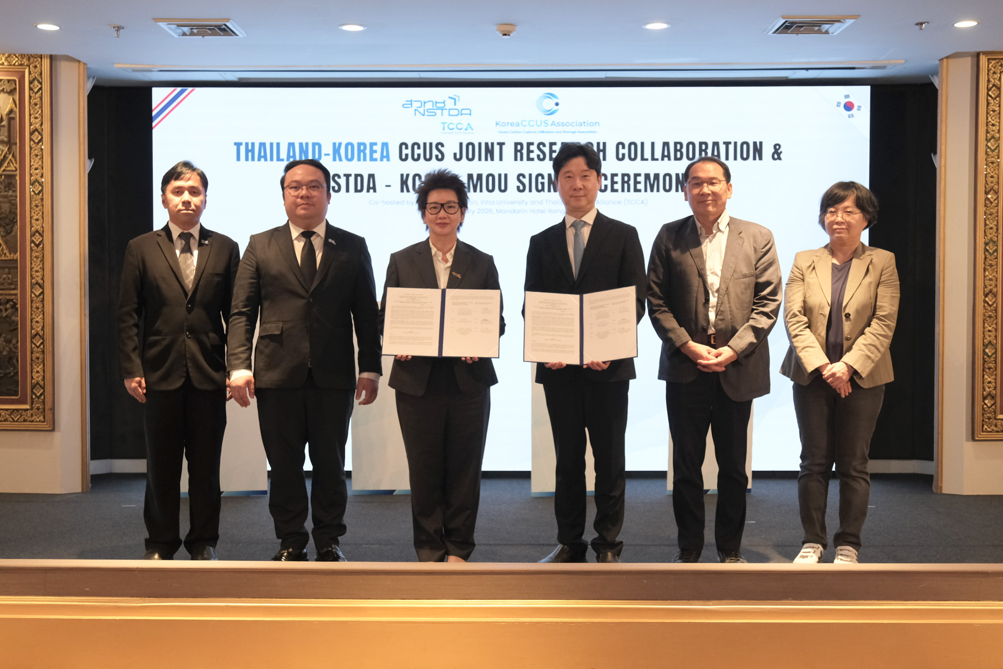 ภาพผู้บริหาร สวทช. และ KCCUS ถือแฟ้มบันทึกข้อตกลง (MOU) ร่วมกันบนเวที โดยมีคณะผู้บริหารร่วมเป็นสักขีพยานในพิธี