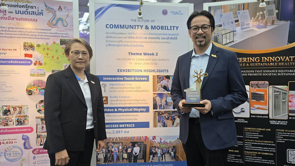 ภาพ: ดร.วรวรงค์ รักเรืองเดช ถ่ายภาพร่วมกันพร้อมโล่ประกาศเกียรติคุณ หน้าป้ายนิทรรศการ The Future of Community & Mobility