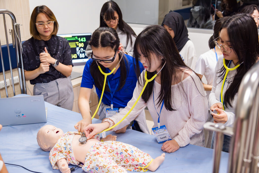 กลุ่มเยาวชนใช้หูฟังตรวจแพทย์ (Stethoscope) ฝึกฟังเสียงหัวใจและปอดบนหุ่นจำลองทารก