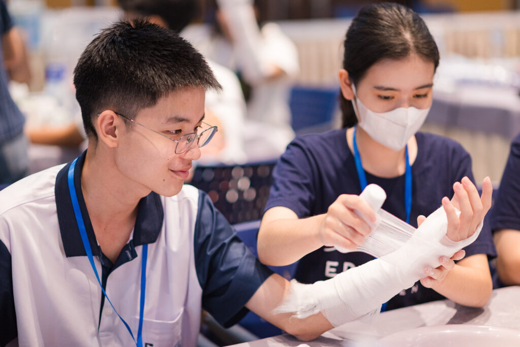 เยาวชนจับคู่ฝึกปฏิบัติการเข้าเฝือกแขนในกิจกรรม Bone Detective & Ortho Lab